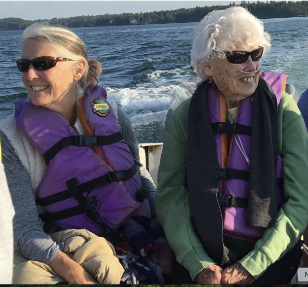 Peggy and her mother riding in a boat on a lake in Maine, both wearing purple life jackets